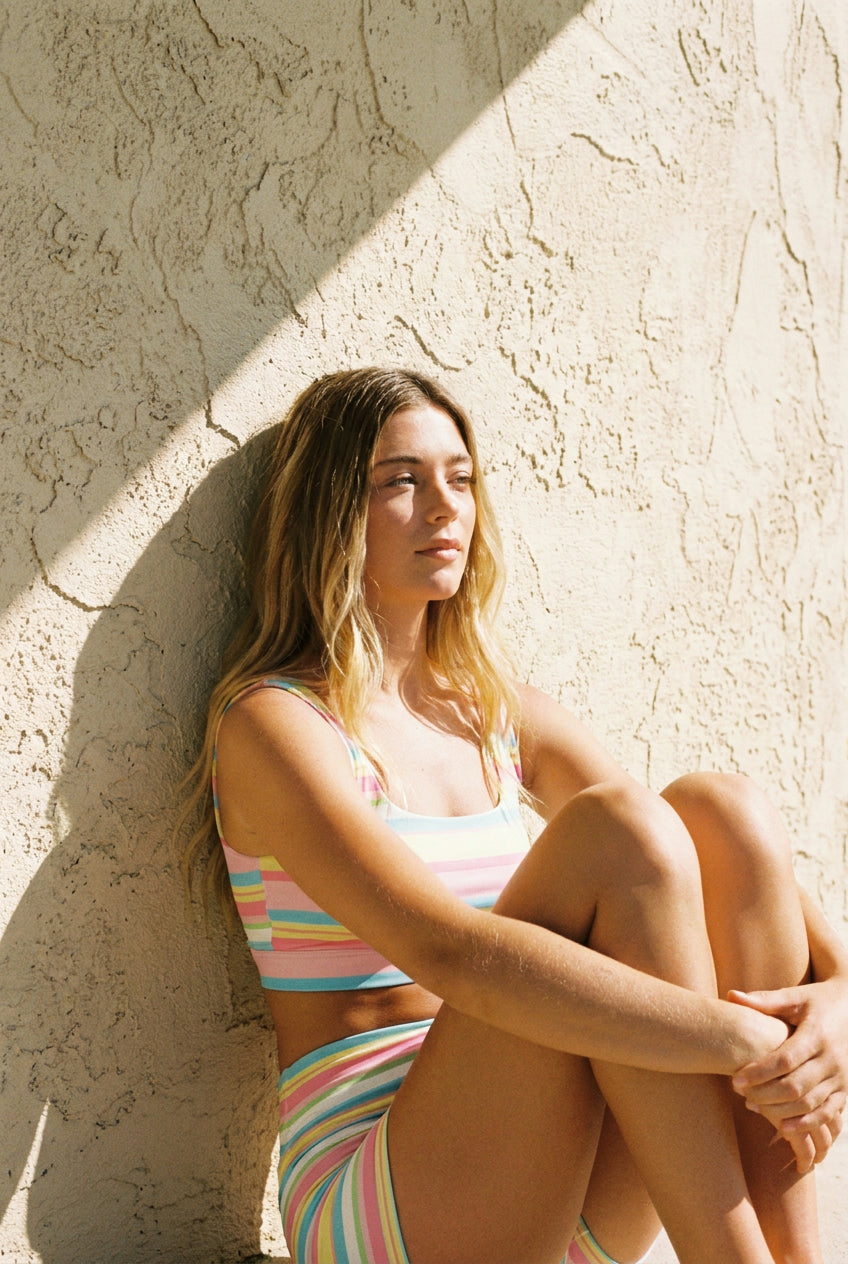 Model in the South Beach Stripe Set seated against a sun-bleached wall
